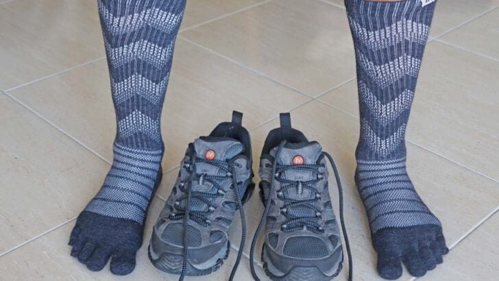 feet wearing toe socks next to grey hiking shoes