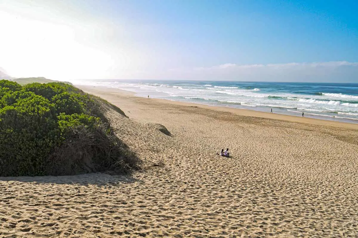 A wide sandy beach with dunes at the sunrise