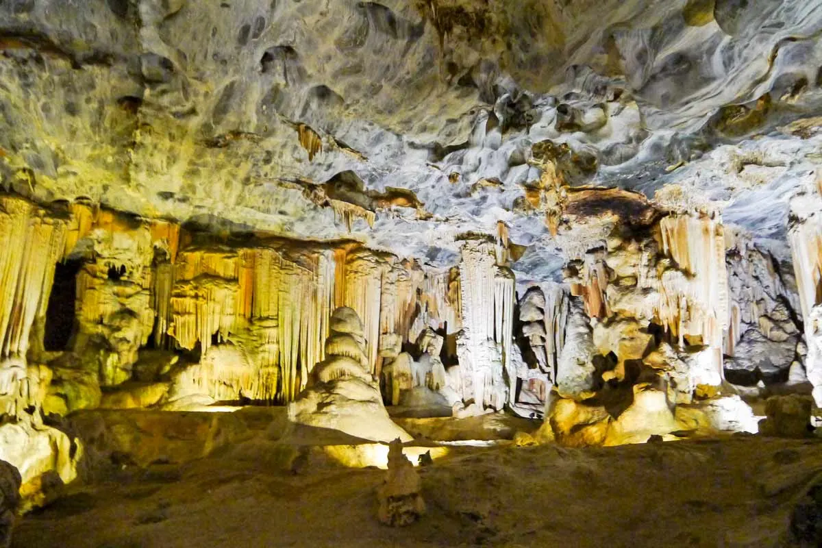 A large cave with yellow lights with massive stalagmites and stalagmites in Oudtshoorn, Garden Route