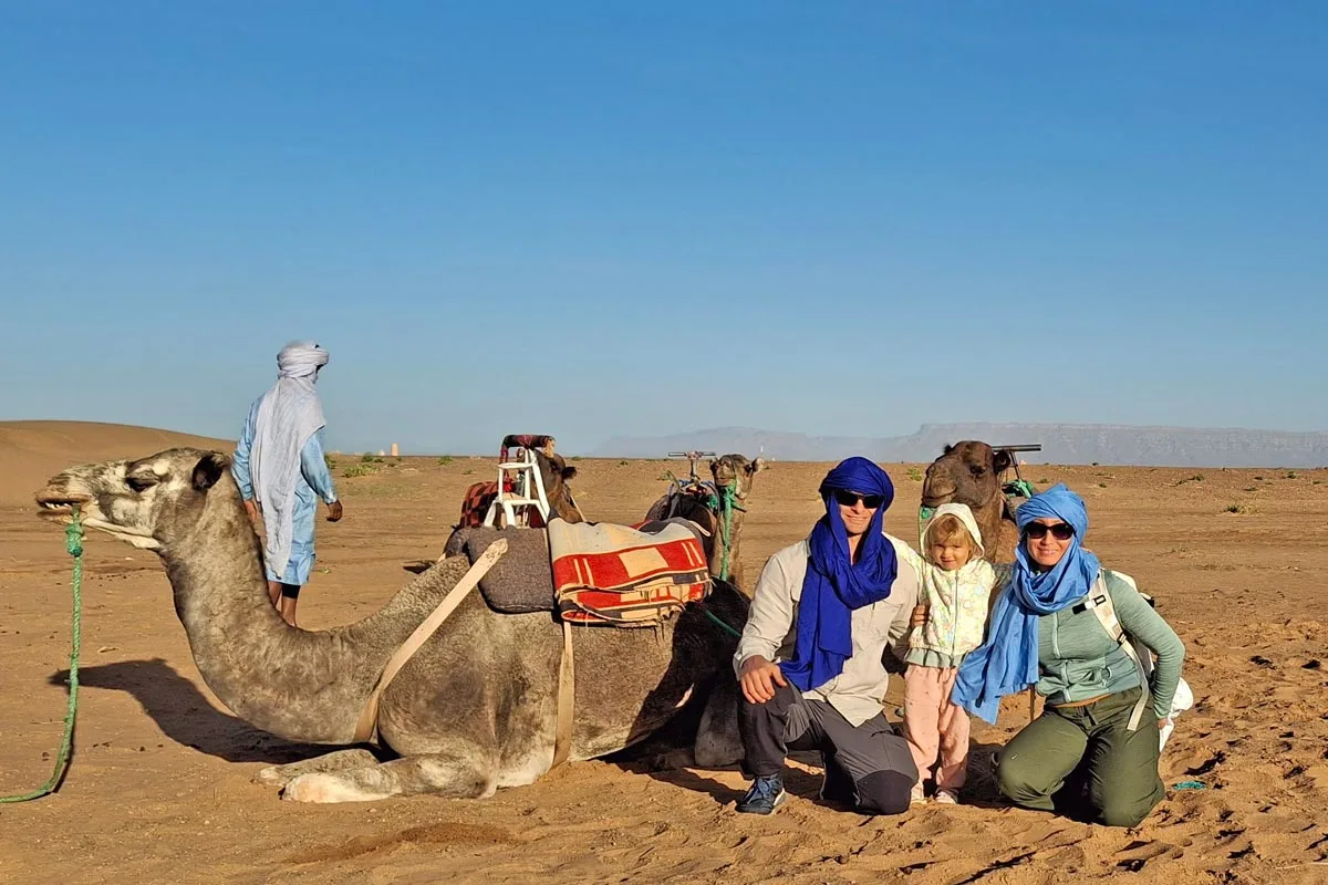 family sitting with a camel in the desert