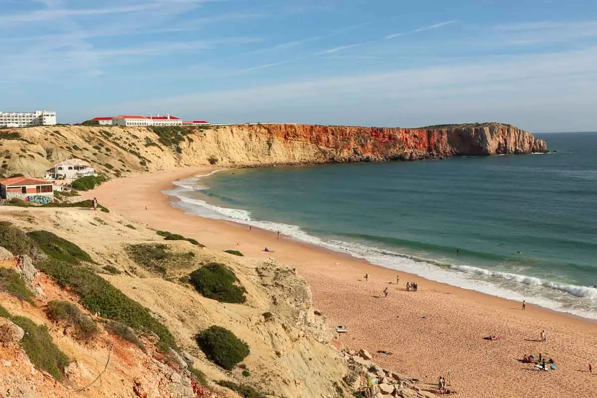long white beach below orange sandstone cliffs