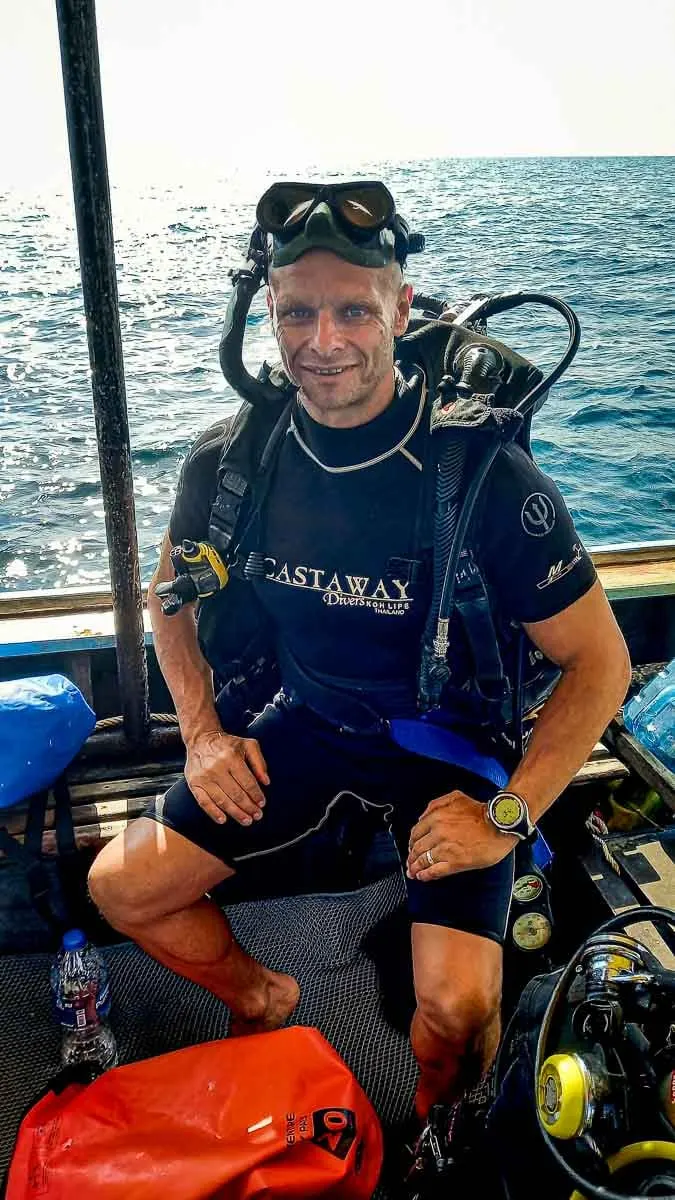 man sitting on boat in scuba gear