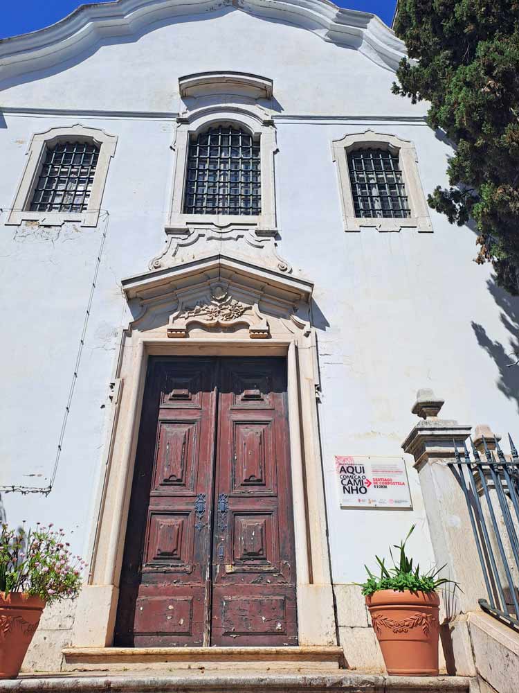 A white facade and a wooden door of a small church in Lisbon