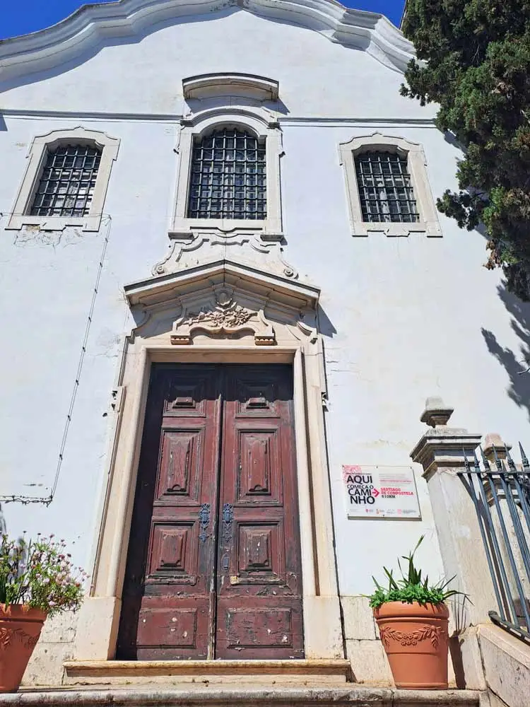 A white facade and a wooden door of a small church in Lisbon