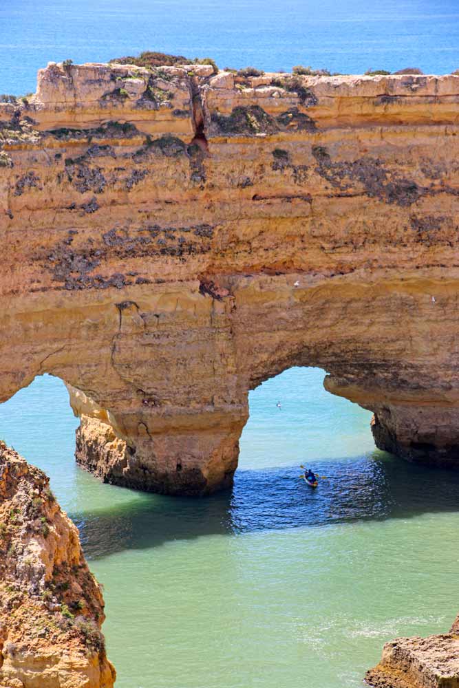 A kayak going through a natural arch in the cliffs of the Algarve