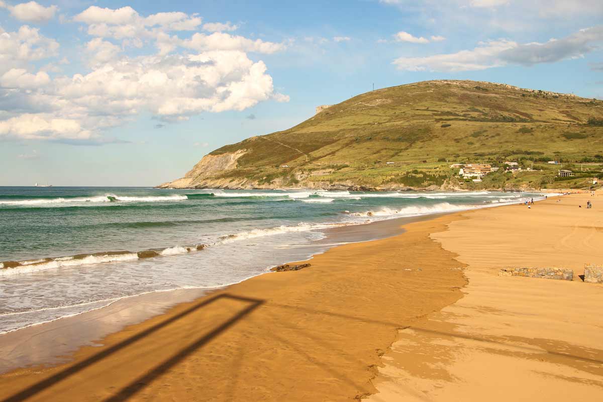 A sandy beach with small waves on the Camino del Norte near Bilbao