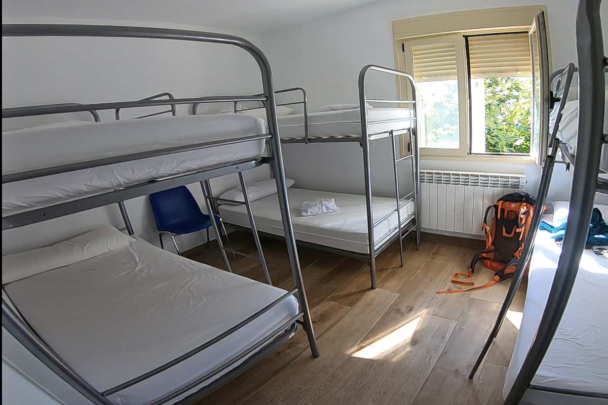 A small dormitory room with 3 metal bunk beds in a municipal albergue on the Camino Frances