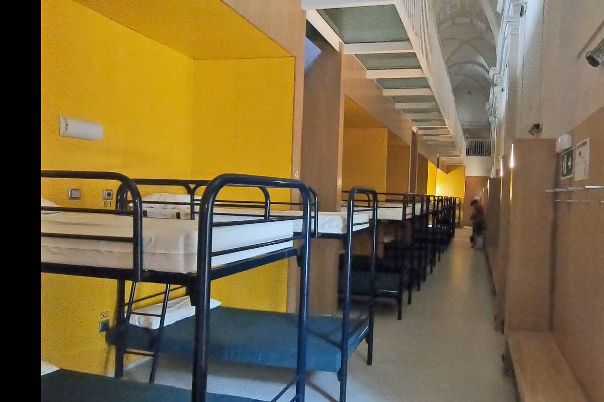A big narrow room with many bunk beds in a public albergue on the French Camino