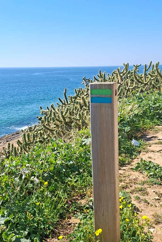A wooden pole with  green and blue strips on the trail from Luz to Salema