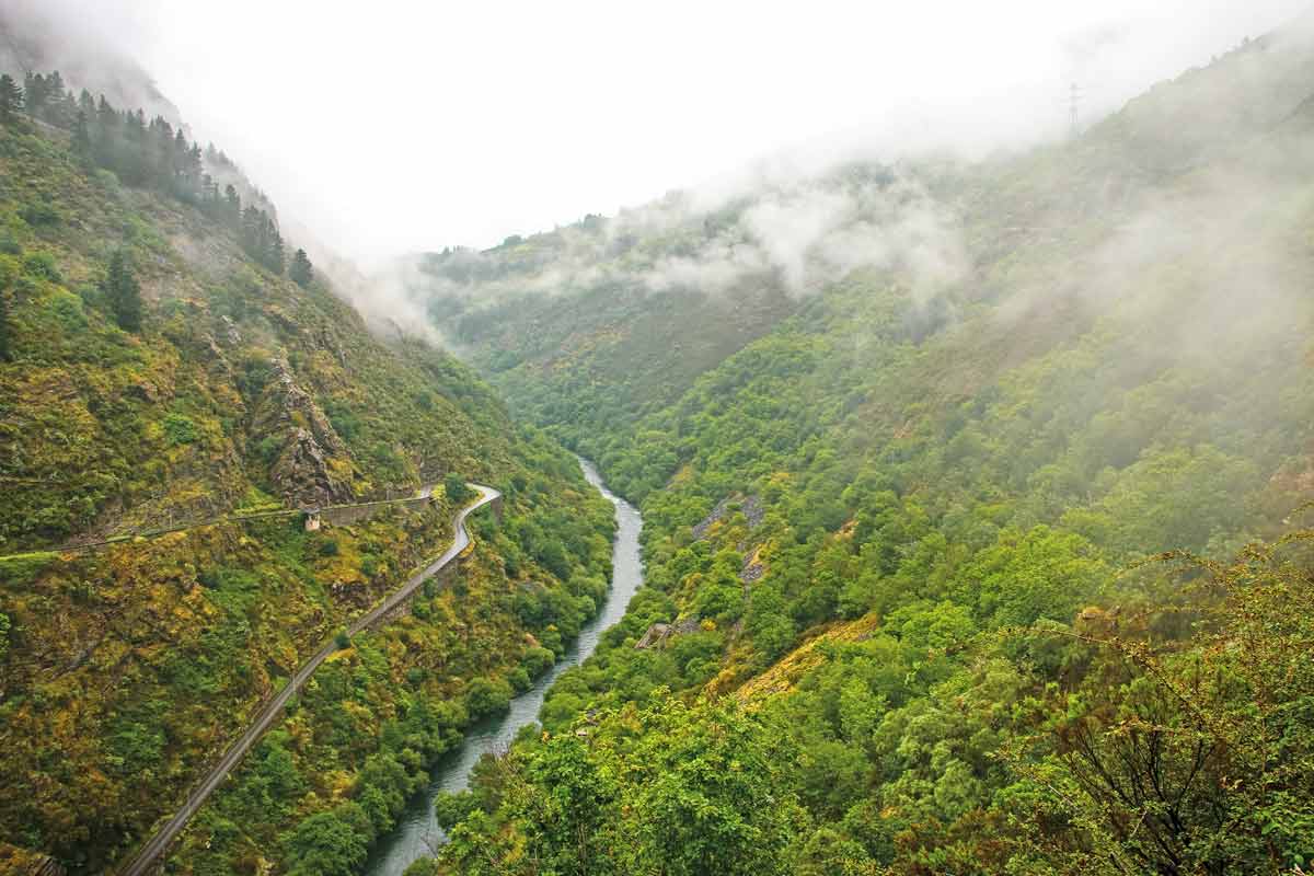 A river between the mountains and a winding road on the slope of the hill in Asturias, Spain