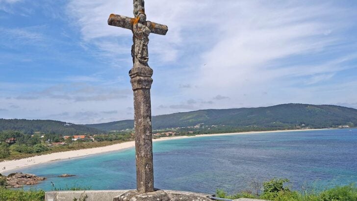 cross on hill overlooking beach and crystal clear ocean