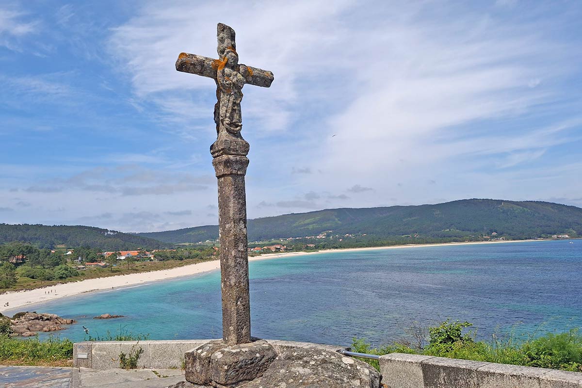 cross on hill overlooking beach and crystal clear ocean