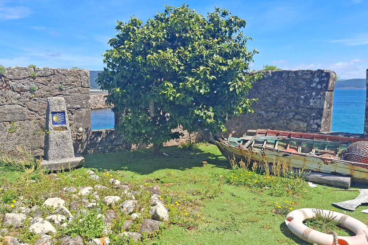 garden in bastion of a castle with fishing boat and Camino de santiago zero marker overlooking the ocean