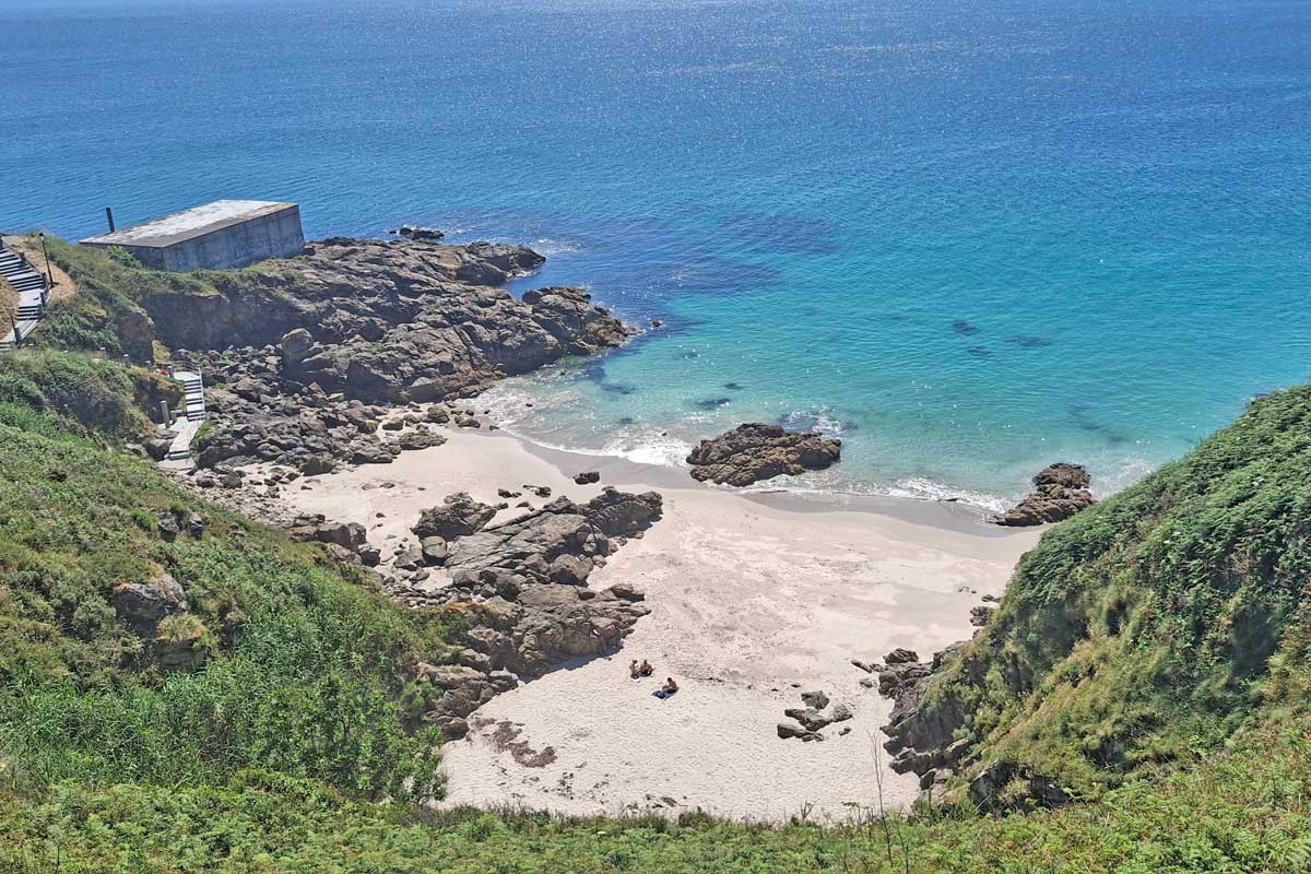 small little hidden beach with clear water below cliffs