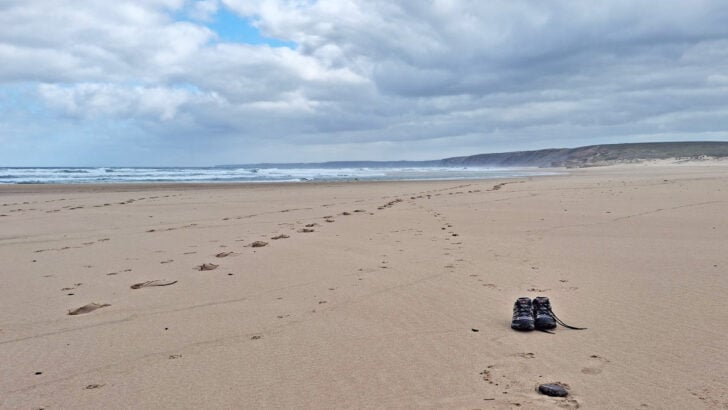 very large beach with pair of hiking shoes standing on the beach