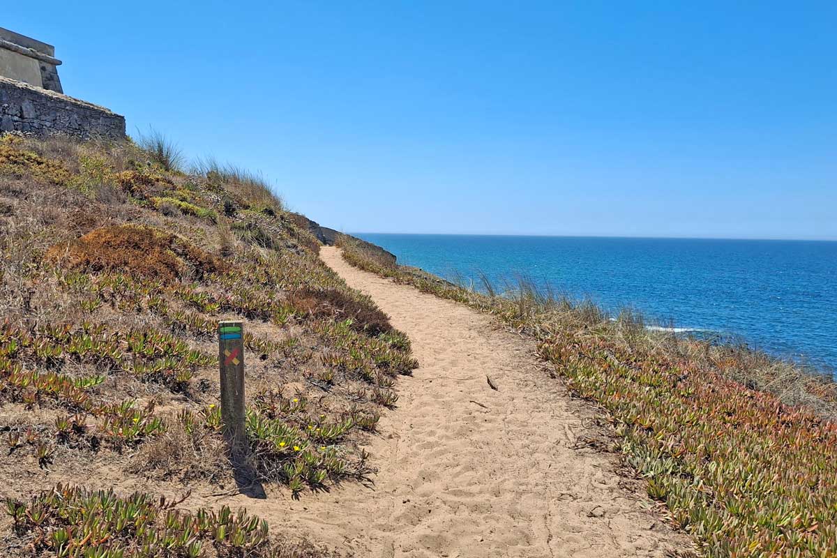 sandy trail, green and blue fishermens trail marker, fort on the right of the trail